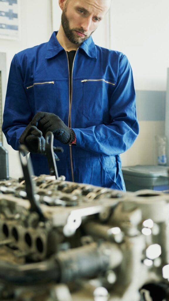 pexels-photo-8985702 A Man in Blue Coveralls Repairing an Engine